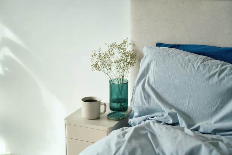 Cama desarrumada com travesseiro amassado de manhã e uma xícara de café no criado-mudo